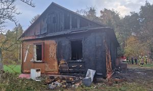 Spalony dom przy którym idzie strażak
